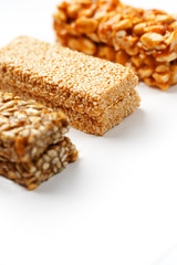 Grain granola bar with peanuts, sesame and seeds in a row on a white background. Top view Three assorted bars, isolate