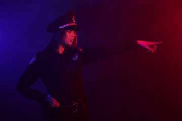 Redheaded female police officer is posing for the camera against a black background with red and...