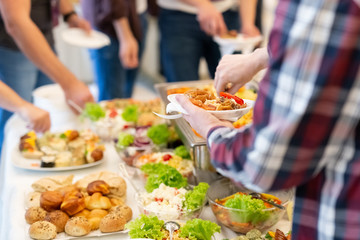 Buffet meal concept. Close up of man hand holding plate with food.
