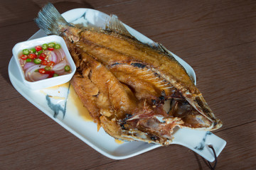 Deep Snapper Fried with fish sauce the delicious favorite menu Thai sea food on wooden table