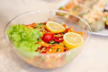 Fresh salad with lemon, cherry tomato, lettuce, cucumber, pepper and carrot.