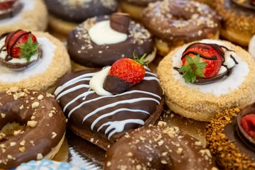 Fototapeta na wymiar Various glazed doughnuts with chocolate, strawberries and hazelnut.