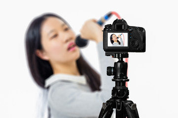 Focus on live view on camera on tripod, teenage girl   with blurred scene in background. Teenage vlogger livestreaming show concept