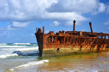 Naklejka premium The rusty wreck of the vessel Maheno on the shores of Fraser Island (Queensland, Australia). The antique rusty and damaged boat and corrosion in the ocean sea.