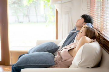 Obraz na płótnie Canvas Young asian couple smile relax comfortable on sofa in the living room in holiday, family leisure and resting with happy in vacation on couch at home, lifestyle and wellbeing concept.