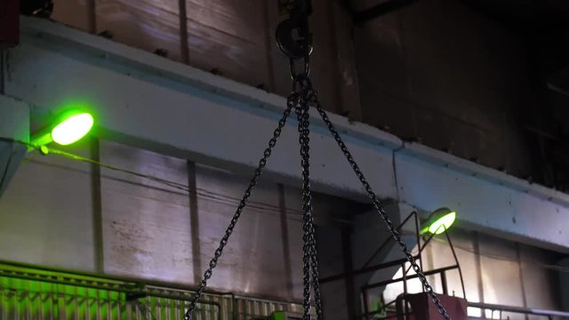 Construction site. Gantry crane hook transports metal sleepers for further construction. Work in a warehouse of metal, transportation of metal products. Loading crane transporting metal sheets 