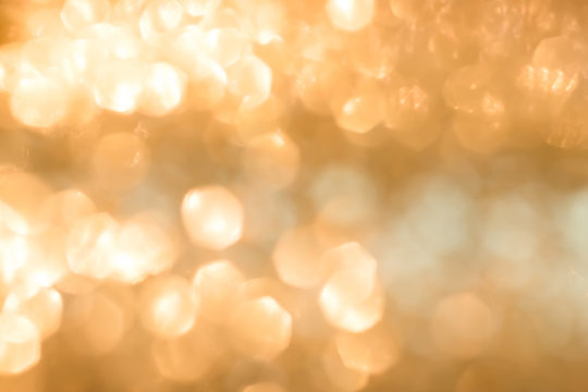 Blur yellow gold bokeh background of reflective glittering light from holiday party crystal ball chandelier