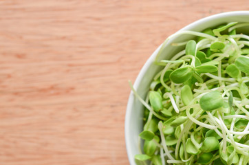 Dish of Salad with green young sunflower sprouts on wooden background.
