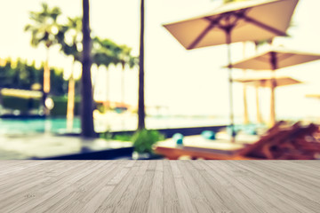 Wood floor with blur summer background tropical resort hotel with blue swimming pool and palm tree