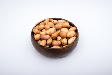 Roasted peanuts in wooden bowl, peanuts are on the isolated on white background