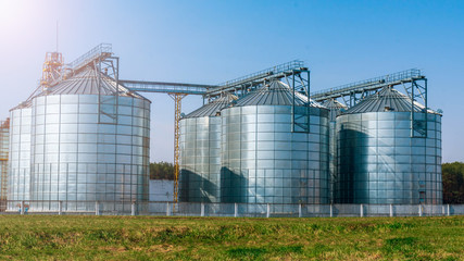 silver silos on agro manufacturing plant for processing drying cleaning and storage of agricultural...