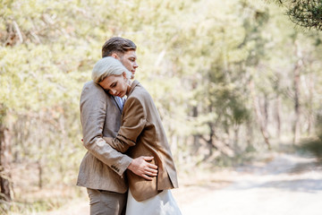 stylish couple in elegant jackets embracing in forest