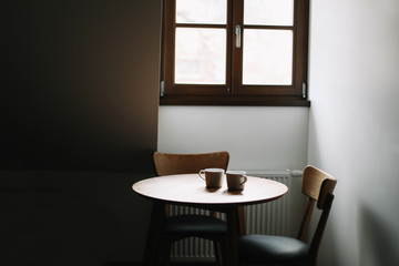 Two cups on wooden table. Dining room with table and two chairs. Modern minimal Scandinavian nordic interior. Morning coffee