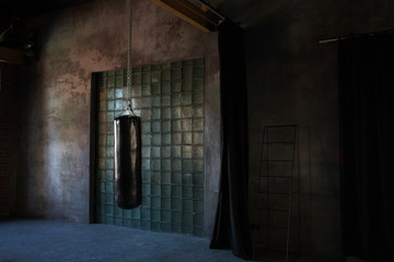Black punching bag in dark grunge gym