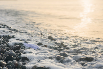 Paper boat lies on the seafront at sunrise.