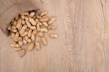 Top view of overturned scattered peanuts, poured roasted peanuts on wooden table, top view