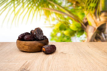 Close up photo of dates, date fruits in bowl and on the wooden table, background is dates tree
