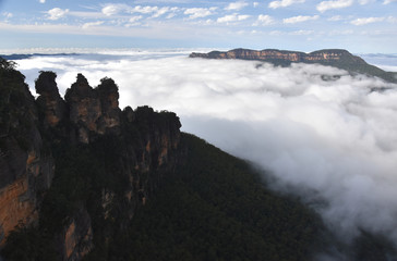 Three Sisters rock formation in the Blue Mountains National Park (NSW, Australia). Jamison Valley is full of with mist after a big rain,