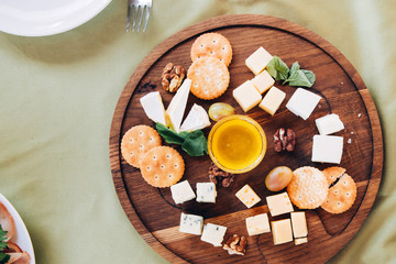 Cheese assortment plate on dark wooden background, free space. Top view on plate with snack on for wine with honey on round catering platter