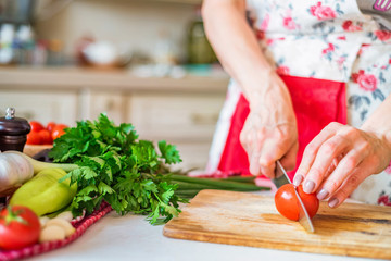 Female hand with knife slices bell pepper in kitchen. Cooking vegetables