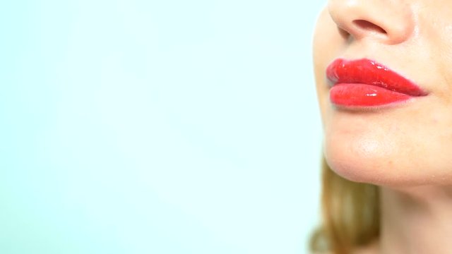 close-up. female lips with red lipstick kiss the mouth of a big raw fish. copy space, blue background