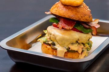 Close up tall tasty burger with cheese served on tray