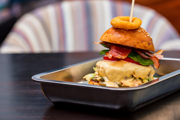 Close up tall tasty burger with cheese served on tray