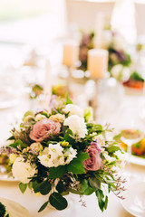 Fototapeta na wymiar Gorgeous luxury wedding table arrangement, floral centerpiece close up. The table is served with cutlery, crockery and covered with a tablecloth. Wedding party decoration with pink and white flowers.