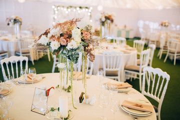 Gorgeous luxury wedding table arrangement, floral centerpiece close up. The table is served with cutlery, crockery and covered with a tablecloth. Wedding party decoration with pink and white flowers.