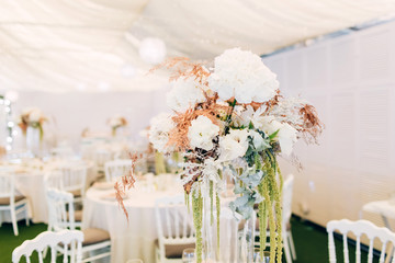 Gorgeous luxury wedding table arrangement, floral centerpiece close up. The table is served with cutlery, crockery and covered with a tablecloth. Wedding party decoration with pink and white flowers.