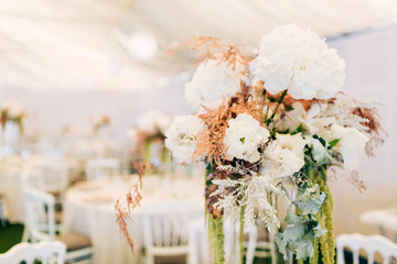 Gorgeous luxury wedding table arrangement, floral centerpiece close up. The table is served with cutlery, crockery and covered with a tablecloth. Wedding party decoration with pink and white flowers.