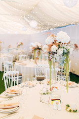 Gorgeous luxury wedding table arrangement, floral centerpiece close up. The table is served with cutlery, crockery and covered with a tablecloth. Wedding party decoration with pink and white flowers.