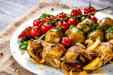 Roast chicken wings, baked potatoes and vegetables