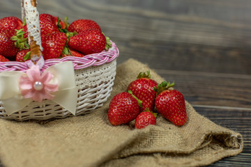 Strawberries in a small basket on the wooden table. Place for your logo or text
