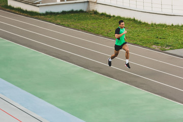 Fototapeta premium full length view of mixed race sportsman running at stadium