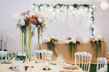 Gorgeous luxury wedding table arrangement, floral centerpiece close up. The table is served with cutlery, crockery and covered with a tablecloth. Wedding party decoration with pink and white flowers.