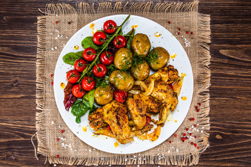 Roast chicken wings, baked potatoes and vegetables