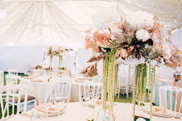Gorgeous luxury wedding table arrangement, floral centerpiece close up. The table is served with cutlery, crockery and covered with a tablecloth. Wedding party decoration with pink and white flowers.