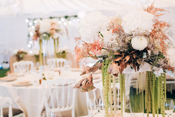Gorgeous luxury wedding table arrangement, floral centerpiece close up. The table is served with cutlery, crockery and covered with a tablecloth. Wedding party decoration with pink and white flowers.