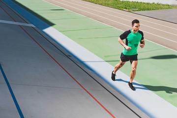 Fototapeta premium full length view of mixed race sportsman running at stadium
