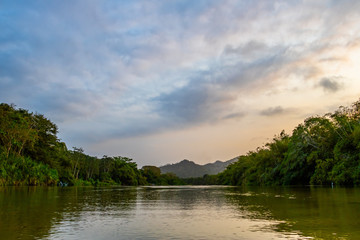Fototapeta na wymiar A wide, shallow river flows calmly through the deep South American jungle at blue violet dusk