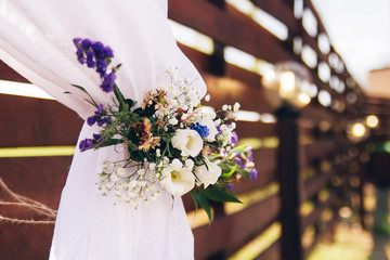 Decorations made of wood and wildflowers served on the festive table setting in rustic style for wedding ceremony. Wooden stage, wall on the restaurant for party.