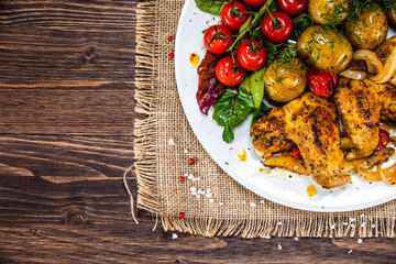 Roast chicken wings, baked potatoes and vegetables