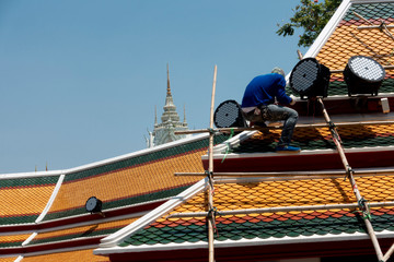 Naklejka premium Worker standing on the wooden stairs on scaffoldin is repairing the roof