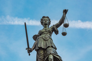 Justitia Figur hält die Waage der Gerechtigkeit hoch