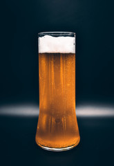 glass flask on a black background with yellow liquid and white foam, a glass of beer on a black background
