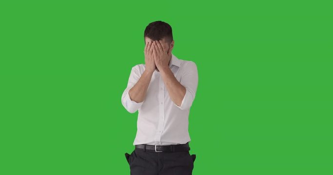 Bankrupt businessman pulling out his empty pockets and crying out loud over green background