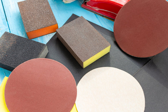 Abrasives, sanding paper sponges and sanding wheel respirator composition on the blue wooden background close up