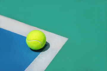 Summer sport concept with tennis ball on white line on hard tennis court. Flat lay, top view, copy space. Blue and green.