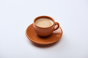delicious coffee with foam in brown cup on saucer on white background